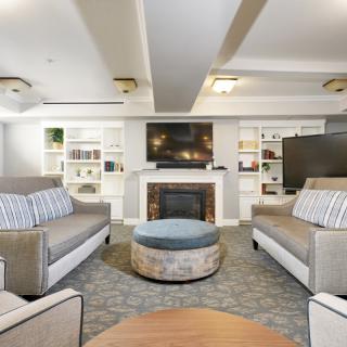 A modern living room with comfortable sofas, a fireplace, and a large television, complemented by bookshelves and elegant lighting.