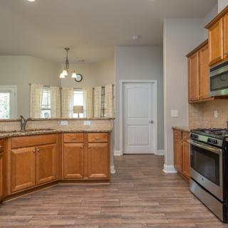 A modern kitchen with wooden cabinets, stainless steel appliances, and a spacious open layout.
