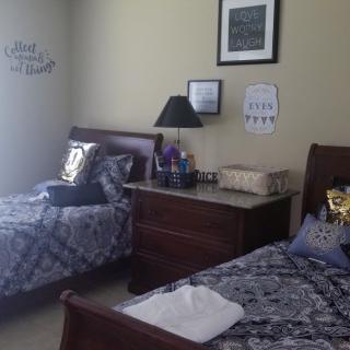 A cozy bedroom with two neatly made double beds, adorned with decorative pillows and wall art.