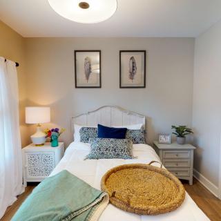 A cozy bedroom interior with a neatly made bed, decorative pillows, and artwork on the walls.