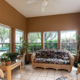 A cozy sunroom with wicker furniture, surrounded by large windows and filled with natural light.