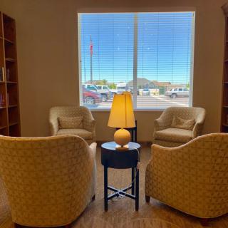 A cozy seating area with four chairs around a lamp, set in front of a large window.