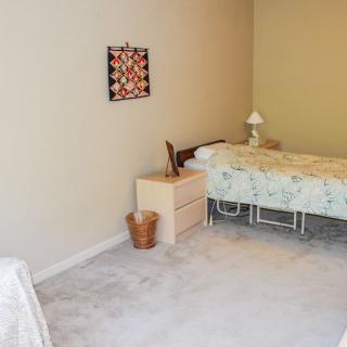 A minimalist bedroom with a single bed, nightstand, and decorative wall art.