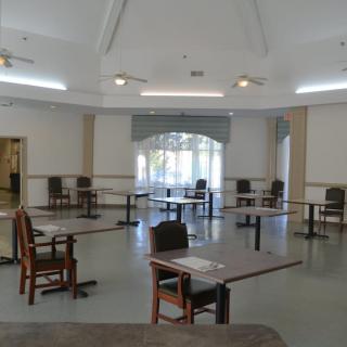 An empty dining room with several tables and chairs arranged in a spacious interior.