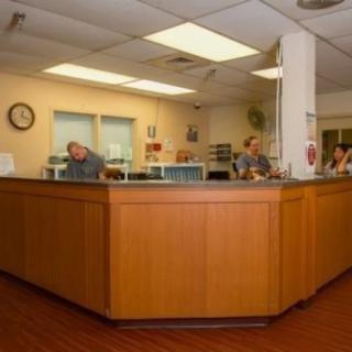A reception area in a medical facility with staff working behind a wooden desk.