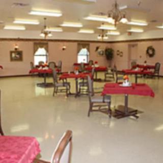A spacious dining hall with tables and chairs, decorated with red tablecloths.