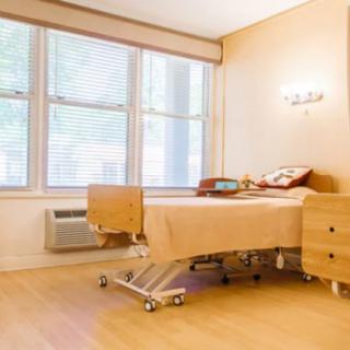 A clean and well-lit hospital patient room with a single bed and large windows.
