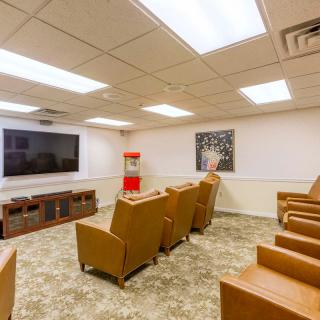 A cozy home theater setup with comfortable recliner seating, a big screen TV, and a popcorn machine for an authentic cinema experience.