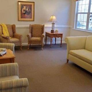 A cozy living room with armchairs, a sofa, and a table under a warm lamp light.