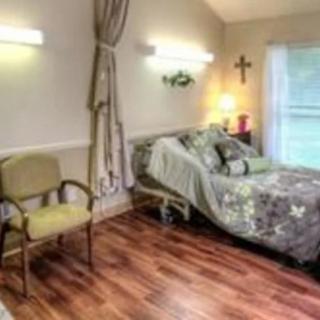 A cozy hospital room with a bed, wooden flooring, and soft lighting.
