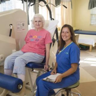 An elderly person undergoing physical therapy with the assistance of a healthcare professional.