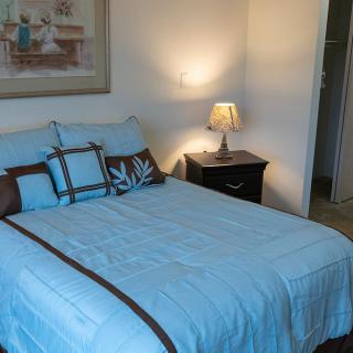 A cozy bedroom with a neatly made bed and a lamp on the nightstand.
