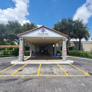 A welcoming entrance to a building with a covered area and lush greenery.