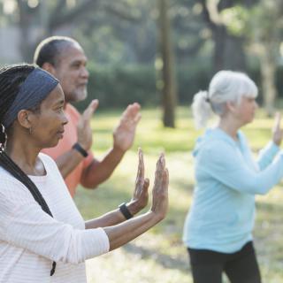 A group of seniors practicing tai chi outdoors for health and wellness.