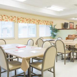 A spacious dining area with neatly arranged tables and chairs, illuminated by natural light.