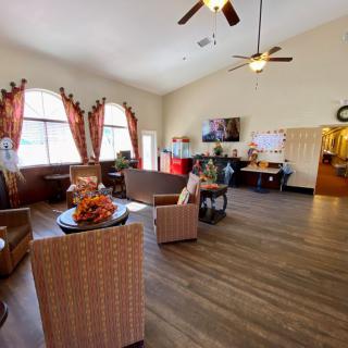 A spacious living room with comfortable seating, wooden floors, and large windows adorned with curtains.