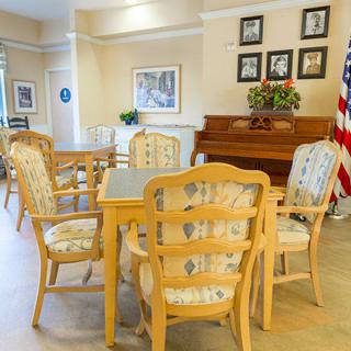 A cozy room featuring a wooden table with chairs, a piano, and decorative elements.