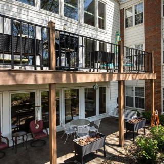 A residential building with a wooden deck and patio area, featuring outdoor furniture.