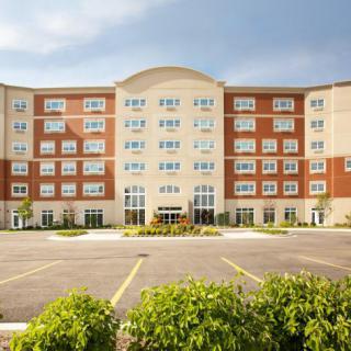 A modern hotel building with a large parking lot in front.