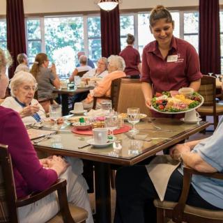 A group of elderly individuals enjoying a meal together in a community dining setting.