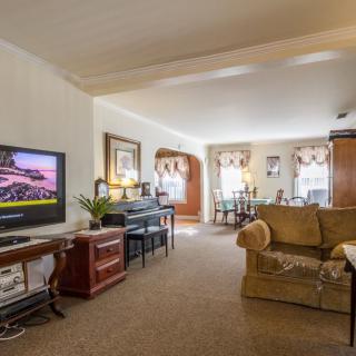 A cozy living room with a television, sofa, and adjacent dining area.