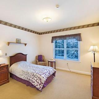 A cozy bedroom with a single bed and traditional decor, featuring a window with a view.