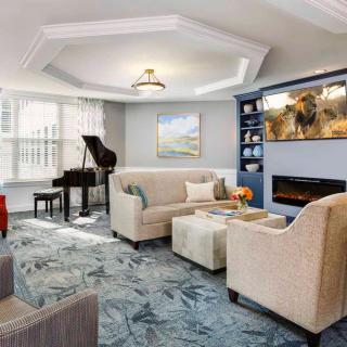 A modern living room featuring a grand piano, comfortable seating, and elegant decor.