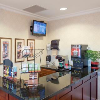 A hotel reception area featuring a coffee station, brochures, and a wall-mounted television.