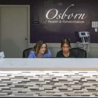 Two employees working at the reception desk of Osborn Health & Rehabilitation.
