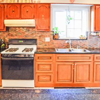A cozy kitchen featuring wooden cabinets, a stove, and a sink under a window.