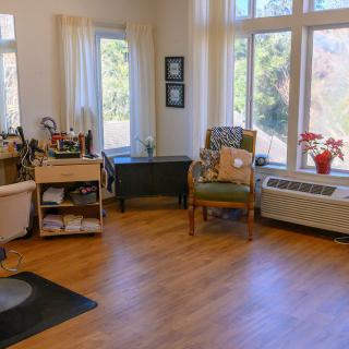 A cozy living room with large windows, wooden flooring, and comfortable seating.