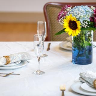 A beautifully set dining table with a vase of colorful flowers and elegant place settings.
