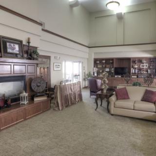 A spacious living room with a large sofa, bookshelves, and a television.