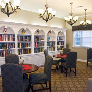 A cozy library room featuring bookshelves, tables, and comfortable chairs.