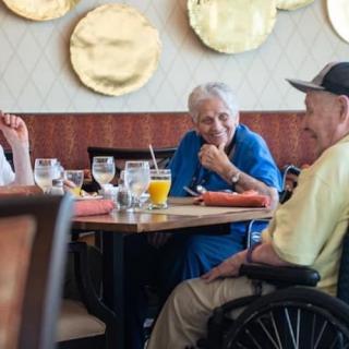 A group of elderly people enjoying a conversation at a restaurant table.