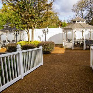 A serene garden with gazebos and a white picket fence.