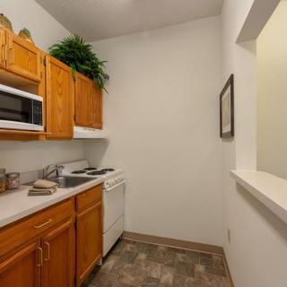 A compact kitchen with wooden cabinets, a microwave, and a dishwasher.