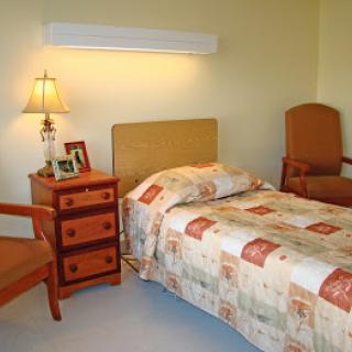 A cozy bedroom with a single bed, nightstand, and chairs.