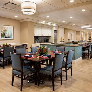 A warmly lit dining area with neatly arranged tables and chairs, featuring elegant decor.