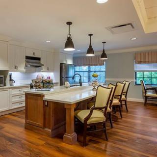 A modern kitchen with a central island, wood flooring, and stylish lighting.