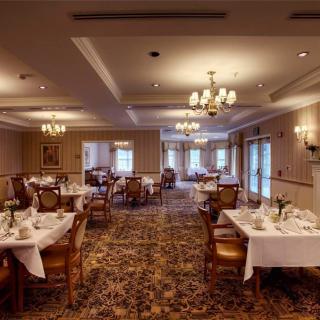 An elegant dining room with neatly arranged tables and chandeliers.