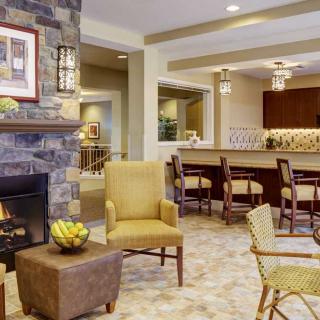 A modern living room with a cozy fireplace and seating area, complemented by a bar counter in the background.