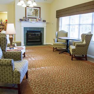 A cozy living room with armchairs, a table, and a fireplace.