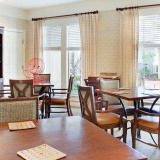 A cozy dining room with tables and chairs near large windows draped with curtains.