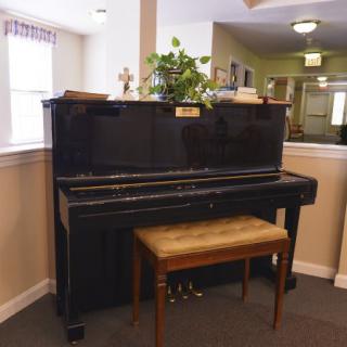 An upright piano with a wooden bench in a cozy indoor setting.