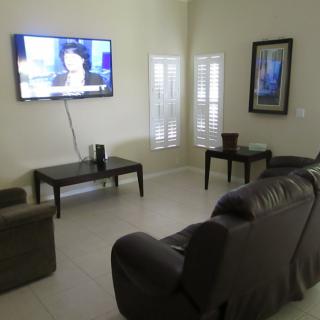 A modern living room with a wall-mounted TV and comfortable seating.