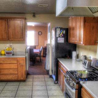 A modern kitchen with wooden cabinets, a gas stove, and a view into the dining area.