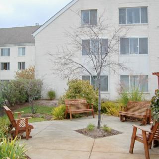 A serene courtyard with wooden benches and lush landscaping outside a residential building.