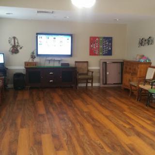 A spacious living room featuring a TV, various pieces of furniture, and wooden flooring.