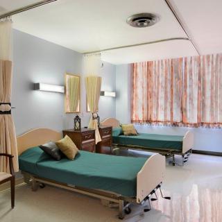 A hospital room with two patient beds and curtains for privacy.